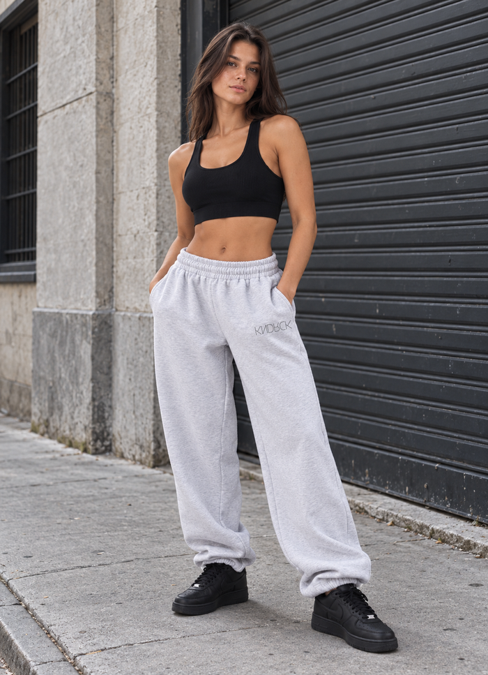 Sive odrasle KNDRCK joggerke – model ob kovinski roleti.